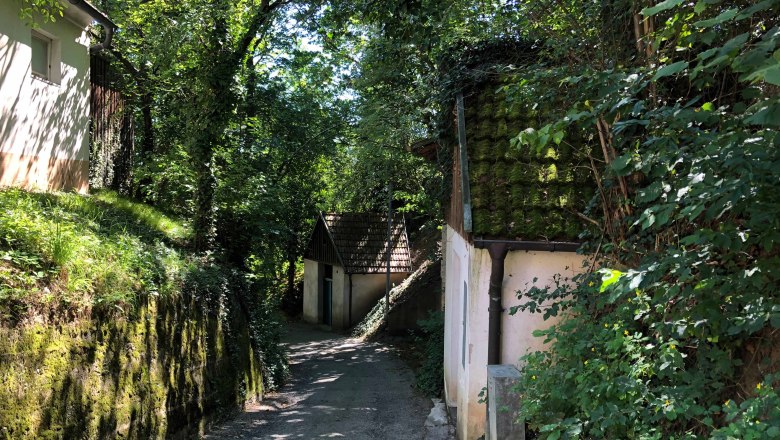 Schmaler Weg durch bewaldetes Gebiet mit alten Gebäuden., © Donau Niederösterreich